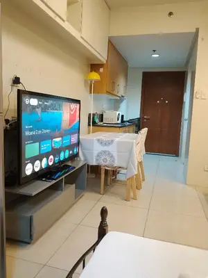 a living room with a flat screen tv and a table at 232D pool view with big balcony in Manila