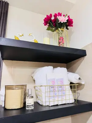 a bathroom shelf with towels and a vase of flowers at Hotel like Condo at Pasay in Manila