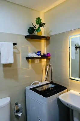 a bathroom with a sink and a washing machine at Serene Stays at Shore in Manila