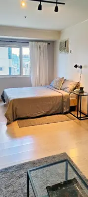 a bedroom with a large bed with a glass table at Private Modern Condo in BGC in Manila