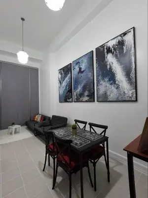 a living room with a table and four paintings on the wall at Forbeswood Garden Suite Parklane BGC in Manila