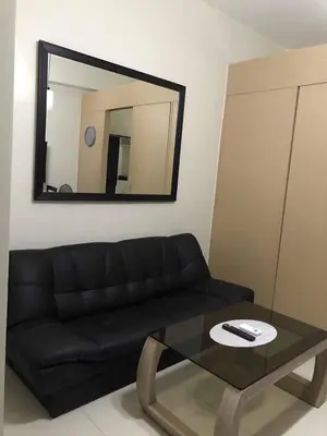 a living room with a black couch and a mirror at Field Residence Staycation in Manila