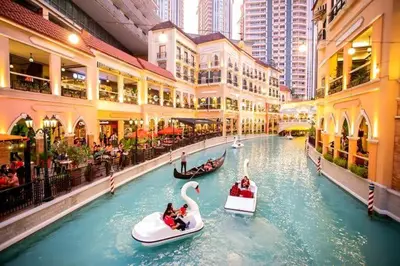 two boats in a canal in a city with buildings at M&M Suites Ridgewood Towers T3 BGC McKinley in Manila