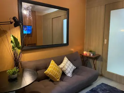 a living room with a couch and a mirror at COZY PASAY CONDOMINIUM HOTEL UNIT with NETFLIX in Manila