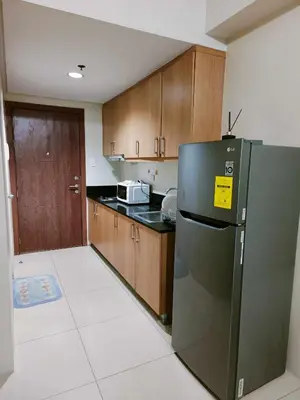 a kitchen with a stainless steel refrigerator and wooden cabinets at 2 bedroom just accross MOA and SMX by jam ez in Manila