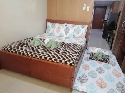 a bedroom with a large bed with a wooden frame at 2 bedroom just accross MOA and SMX by jam ez in Manila