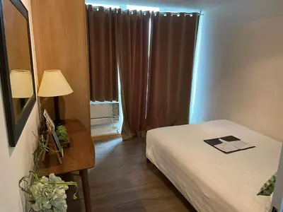 a room with a bed and a table and a window at Cozy fully furnished 2 BR unit in Manila