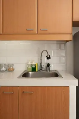 a kitchen with a stainless steel sink and wooden cabinets at Studio Penthouse in Greenbelt - Park View & Pool in Manila