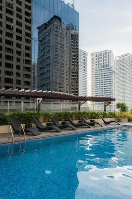 a large swimming pool with chairs and buildings at Studio Penthouse in Greenbelt - Park View & Pool in Manila
