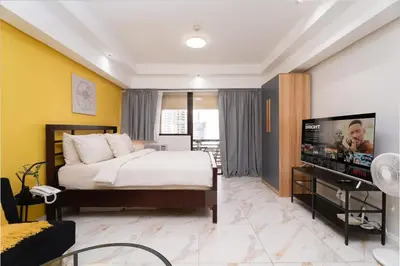 a bedroom with a bed and a flat screen tv at Greenbelt Makati Condo with Balcony & Park Views in Manila