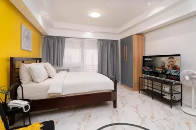 a bedroom with a bed and a flat screen tv at Greenbelt Makati Condo with Balcony & Park Views in Manila