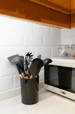 a container of kitchen utensils sitting next to a microwave at Charming Greenbelt Condo with Balcony & Pool Access in Manila