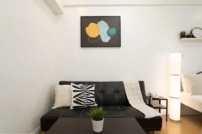 a living room with a black leather couch at Comfy Greenbelt Suite - Fiber Wifi & Free Pool in Manila