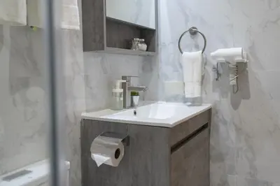 a bathroom with a sink and a roll of toilet paper at Comfy Greenbelt Suite - Fiber Wifi & Free Pool in Manila