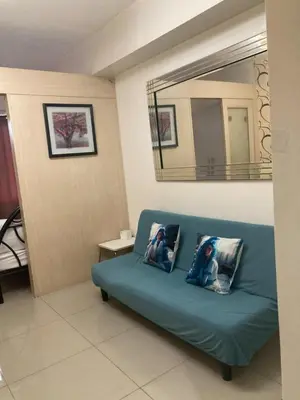 a blue couch in a room with a mirror at Sea Residence Tower EF by Theresa P in Manila