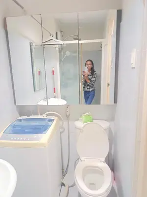a woman taking a picture of a bathroom with a toilet at Sea Residence Tower EF by Theresa P in Manila