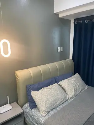 a bedroom with a bed with a large headboard at Studio for 4 with Netflix, 55in TV, 200Mbs net, in heart of Makati in Manila