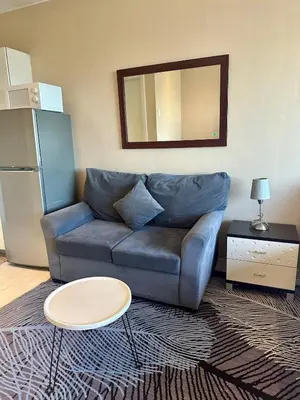 a living room with a couch and a mirror at Studio Unit with Balcony in The Gramercy Residences in Manila