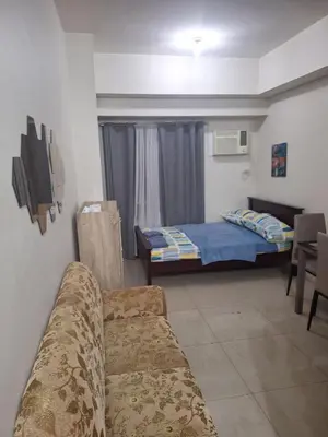 a living room with a bed and a couch at Chelsea Suites at the Beacon Makati in Manila