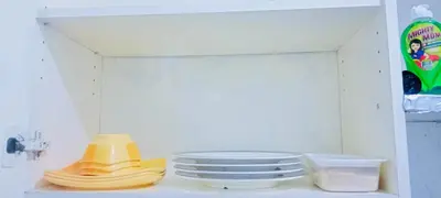 a shelf with plates and a stack of yellow dishes at Avida sm sucat condotel in Manila