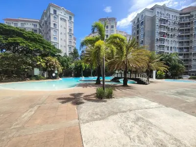a swimming pool with palm trees and tall buildings at Two Bedroom - Presidio Lakefront in Manila