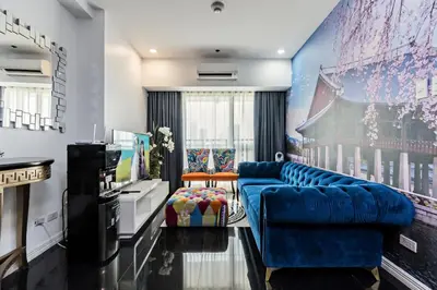 a living room with a blue couch and a television at Makati City Centre Condo in Manila