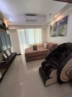 a bedroom with a bed and a couch and a television at Staycation By Abby Tower E in Manila