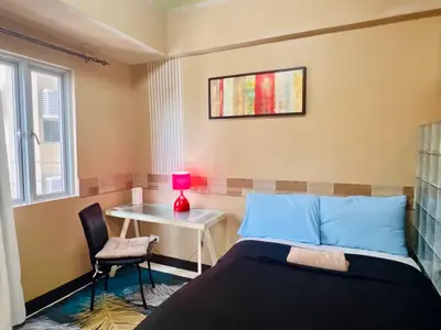 a bedroom with a bed and a table and a lamp at BGC Mckinley City Center Apartments in Manila