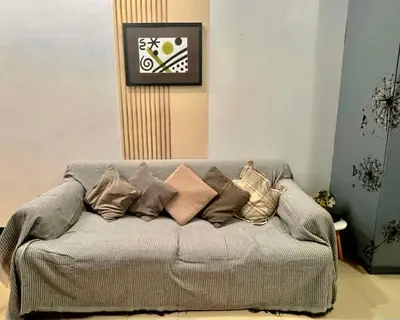 a couch with many pillows on it with a clock at BGC Mckinley Center Prime Accommodations in Manila