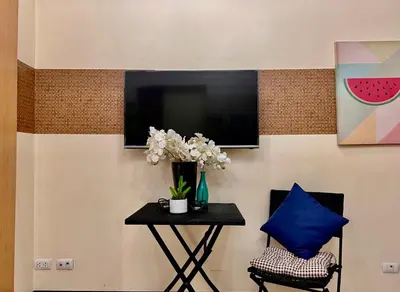 a table with a vase of flowers and a tv at BGC Mckinley Center Prime Accommodations in Manila
