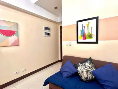 a room with a couch and paintings on the wall at BGC Mckinley Center Prime Accommodations in Manila