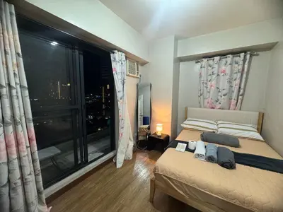 a bedroom with a bed and a large window at FLAIR Condotel 1 BR Near MRT EDSA Shangrila Megamall Lightmall in Manila