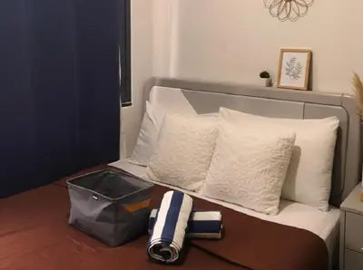 a bed with white pillows and a bag on it at Mall Of Asia - Aseana Prime Accommodations in Manila