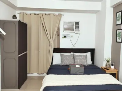 a bedroom with a bed with a blue comforter at Mall Of Asia - Aseana Prime Accommodations in Manila