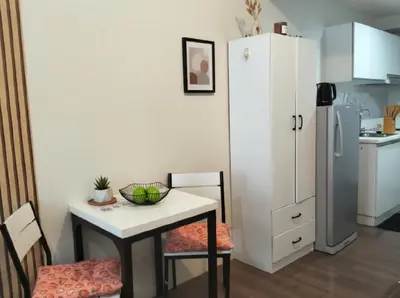 a small kitchen with a table and a white refrigerator at Makati Business District Prime Accommodations in Manila