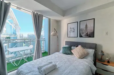 a bedroom with a bed and a balcony with a table at Bahamas Tower Azure Urban Resort Residences by Nestled Nook in Manila