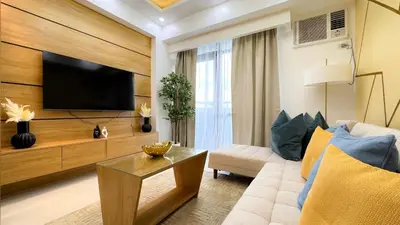 a living room with a couch and a tv at CYLOS PLACE Manhattan Araneta Center 2BR with BALCONY in Manila
