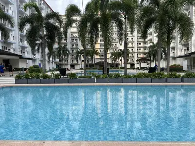 a swimming pool in front of a building with palm trees at SMDC Field REsidences condo unit in Manila