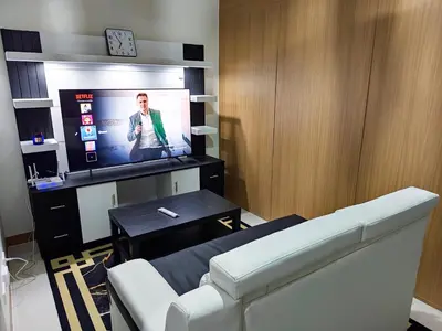 a living room with a white couch and a tv at StayCation at Red Residence in Manila