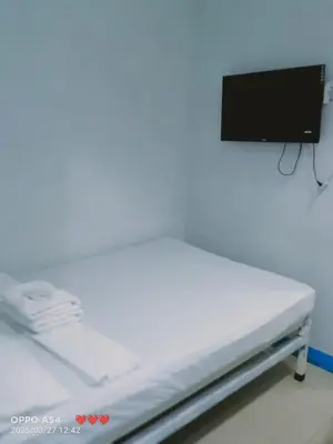 a white bed in a room with a tv on the wall at AIr Hub Transient in Manila