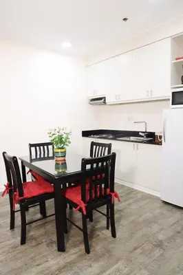 a kitchen with a black table and chairs and a refrigerator at Home Away From Home in Manila