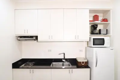 a kitchen with white cabinets and a sink and a microwave at Home Away From Home in Manila
