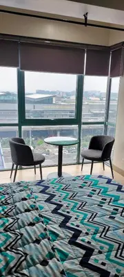 two chairs and a table in a room with windows at Kylie and Drew Room Near Airport in Manila