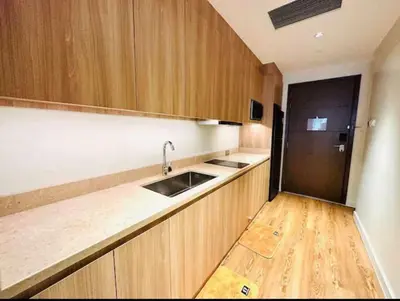 a kitchen with wooden cabinets and a sink and a refrigerator at Novotel Executive Suite - Acqua Manila 2905 in Manila