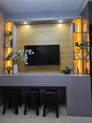 a kitchen with a table with stools and a tv on a wall at Sakura Suites At Mall of Asia Near Airport in Manila