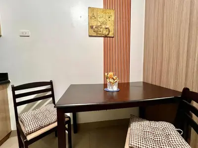 a dining room table with a vase of flowers on it at Very Central Mall of Asia Manila Apartment in Manila