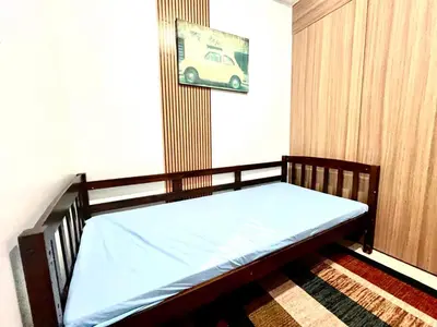 a wooden bed in a room with a picture of a car at Very Central Mall of Asia Manila Apartment in Manila