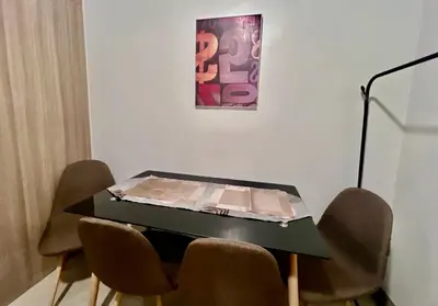 a table with chairs in a room with a painting at MOA - Aseana Value for Money Super Cozy Condo in Manila