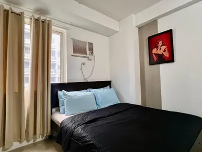 a bedroom with a bed and a window at Mall of Asia Shore Residence - Perfect Location in Manila