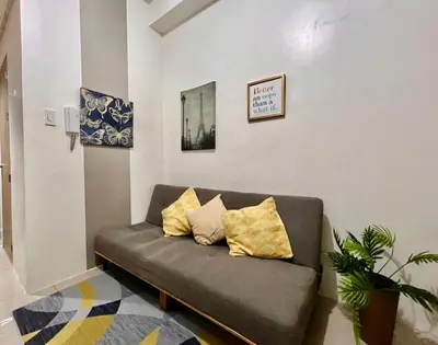 a couch in a living room with two pillows on it at Mall of Asia Shore Residence - Perfect Location in Manila